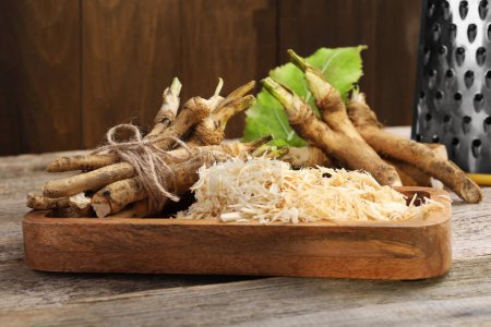 Photo for Grated horseradish and roots on wooden table, closeup - Royalty Free Image