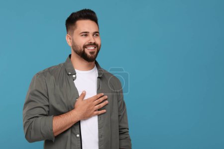 Thank you gesture. Happy grateful man with hand on chest against light blue background, space for text