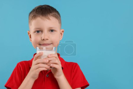 Téléchargez les photos : Garçon mignon avec verre de lait frais sur fond bleu clair, espace pour le texte - en image libre de droit