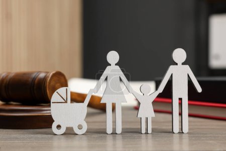Téléchargez les photos : Droit de la famille. Figure des parents avec enfants, livres et marteau sur table en bois - en image libre de droit