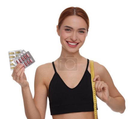 Foto de Mujer joven feliz con pastillas y cinta métrica sobre fondo blanco. pérdida de peso - Imagen libre de derechos