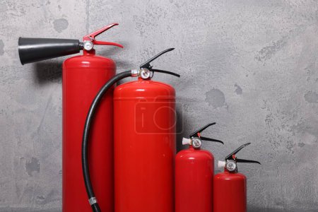 Photo for Four red fire extinguishers near grey wall - Royalty Free Image