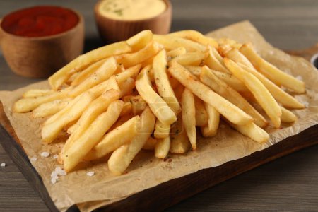 Delicious french fries on wooden table, closeup view