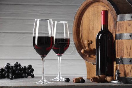 Köstlicher Wein, Holzfässer und reife Trauben auf hellgrauem Tisch