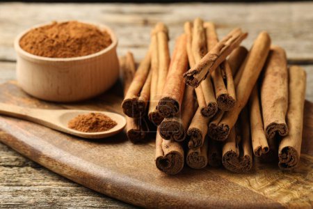 Photo for Cinnamon powder and sticks on wooden table, closeup - Royalty Free Image
