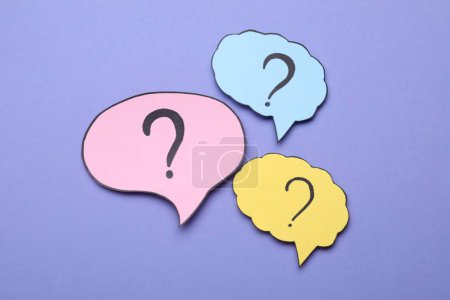 Photo for Different paper speech bubbles with question marks on violet background, flat lay - Royalty Free Image