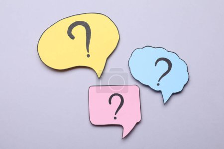 Photo for Different paper speech bubbles with question marks on light grey background, flat lay - Royalty Free Image