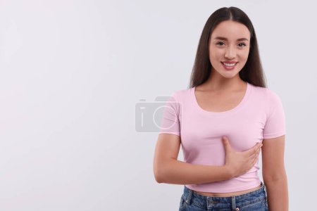Beautiful happy woman doing breast self-examination on white background, space for text
