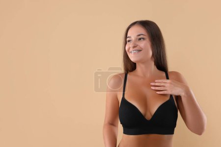 Téléchargez les photos : Portrait de jeune femme avec un beau sein sur fond beige. Espace pour le texte - en image libre de droit