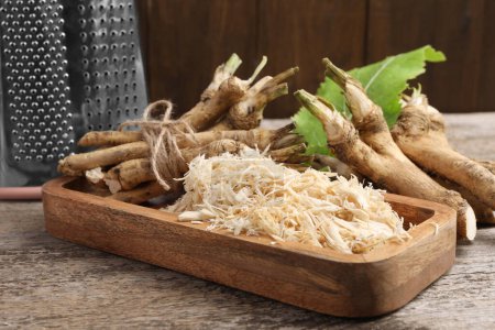 Photo for Grated horseradish and roots on wooden table, closeup - Royalty Free Image
