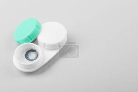 Case with blue contact lenses on light grey background, space for text