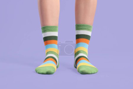 Woman in stylish colorful socks on violet background, closeup