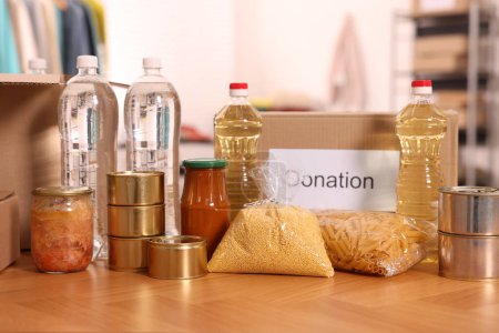 Téléchargez les photos : Volontariat. Différents produits alimentaires et boîtes en carton sur la table dans l'entrepôt - en image libre de droit