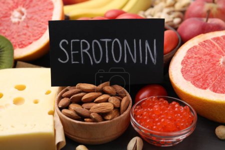 Foto de Muchos productos diferentes y tarjeta con palabra Serotonina en la mesa, primer plano. Antidepresivos naturales - Imagen libre de derechos