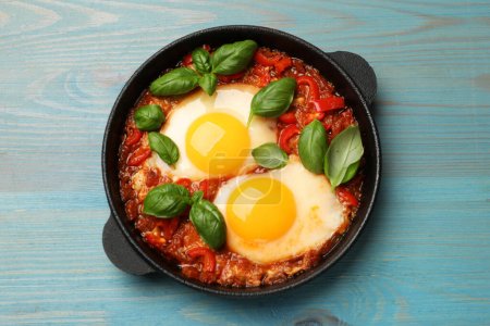 Delicious Shakshuka on light blue wooden table, top view