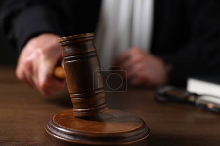 Photo for Judge with gavel sitting at wooden table, closeup - Royalty Free Image
