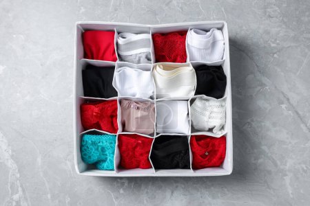Photo for Organizer with folded women's underwear on light grey marble table, top view - Royalty Free Image