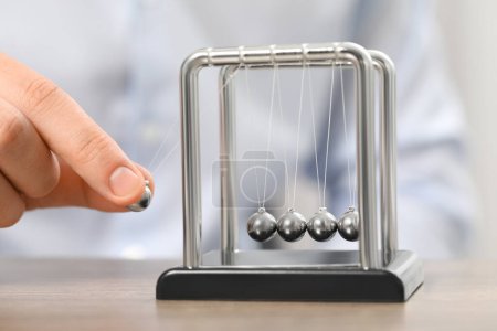 Photo for Man playing with Newton's cradle at table, closeup. Physics law of energy conservation - Royalty Free Image