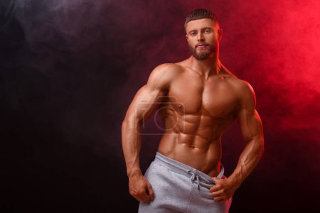 Photo for Young bodybuilder with muscular body in smoke on color background, space for text - Royalty Free Image