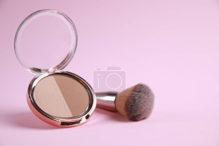 Face powder and brush on pink background, space for text