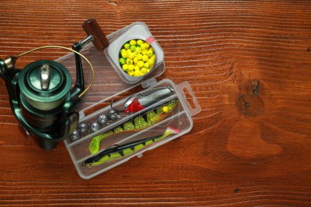 Photo for Fishing tackle. Spinning reel, lures and bait on wooden table, flat lay. Space for text - Royalty Free Image