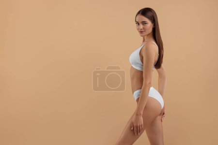 Foto de Mujer joven en elegante bikini blanco sobre fondo beige. Espacio para texto - Imagen libre de derechos