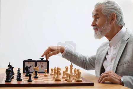 Hombre encendiendo el reloj de ajedrez durante el torneo en la mesa contra fondo blanco