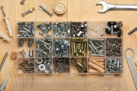 Photo for Organizer with many different fasteners and wrenches on wooden table, flat lay - Royalty Free Image