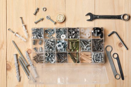 Photo for Organizer with many different fasteners and wrenches on wooden table, flat lay - Royalty Free Image
