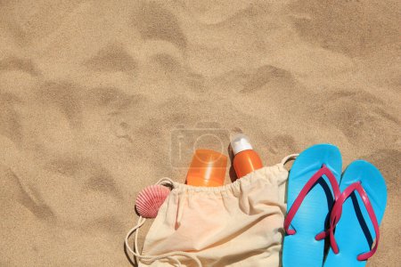 Sonnencreme, Muschel- und Strandaccessoires auf Sand, flach gelegt. Raum für Text