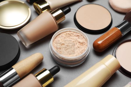 Face powders and other makeup products on grey background, closeup