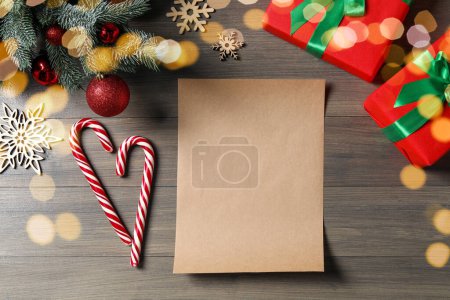 Foto de Composición plana con hoja de papel en blanco, bastones de caramelo y decoración de Navidad en mesa de madera, espacio para el texto. Carta a Santa - Imagen libre de derechos