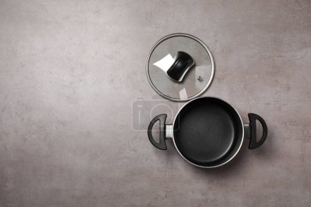 Photo for One empty black pot and glass lid on grey textured table, flat lay. Space for text - Royalty Free Image