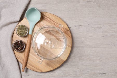 Photo for One empty glass pot, ladle and spices on light wooden table, top view. Space for text - Royalty Free Image
