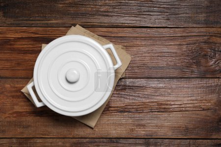 Photo for White ceramic pot with lid on wooden table, top view. Space for text - Royalty Free Image
