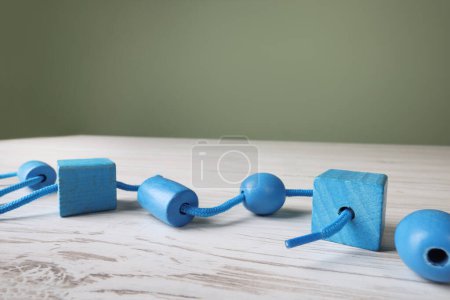Wooden lacing toy on light table, closeup and space for text. Motor skills development