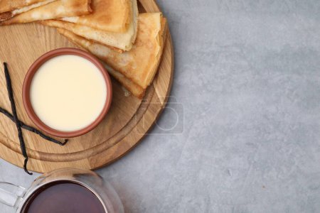 Téléchargez les photos : Crêpes savoureuses servies avec du lait condensé sur une table grise, plat. Espace pour le texte - en image libre de droit