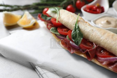 Photo for Delicious sandwich with bresaola, tomato, onion and cheese on light grey table, closeup. Space for text - Royalty Free Image