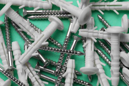 Photo for Many metal screws and white dowels on turquoise background, closeup - Royalty Free Image