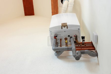 Modern gas boiler on beige wall indoors, low angle view. Space for text