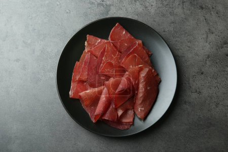 Photo for Plate with tasty bresaola on grey table, top view - Royalty Free Image