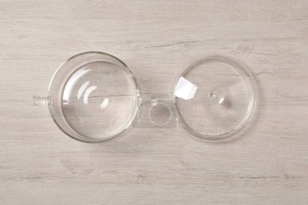Una olla de vidrio vacía y una tapa sobre una mesa de madera clara. plano laico