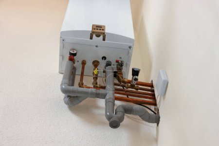 Modern gas boiler on white wall indoors, low angle view
