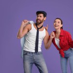 Happy couple dancing together on violet background, space for text