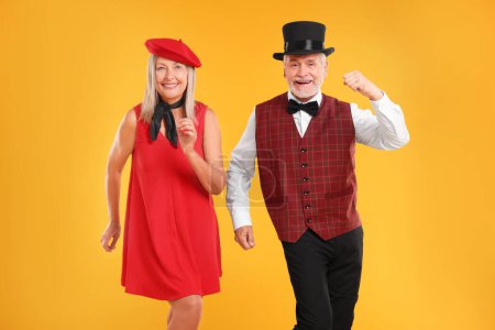 Senior couple dancing together on orange background