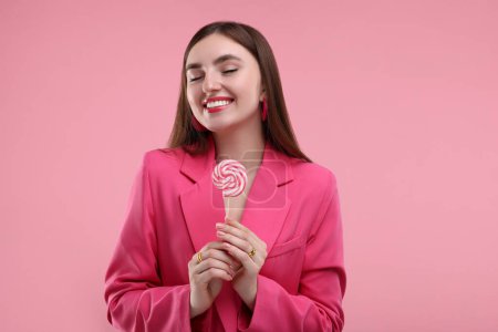Pink look. Beautiful woman with lollipop on color background