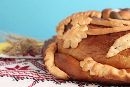 Rushnyk with korovai on table against light blue background, closeup. Ukrainian bread and salt welcoming tradition