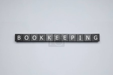 Word Bookkeeping made with black cubes on light grey background, top view