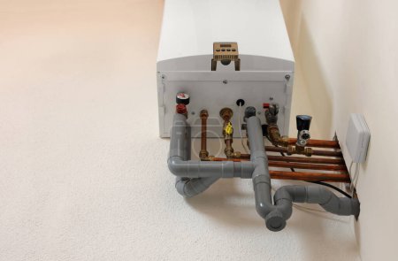 Modern gas boiler on white wall indoors, low angle view. Space for text