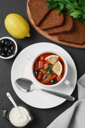 Téléchargez les photos : Soupe solyanka à la viande avec saucisses, olives et légumes servis sur table texturée gris foncé, plat - en image libre de droit